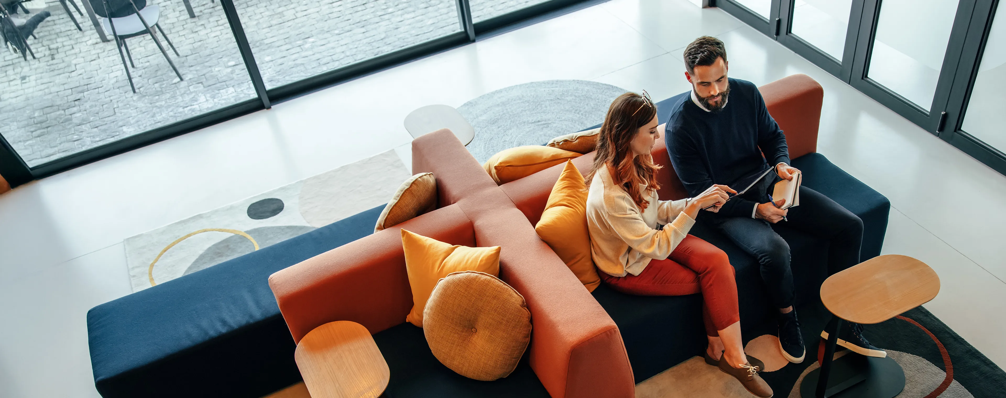 Two colleagues sitting in a lobby looking at papers