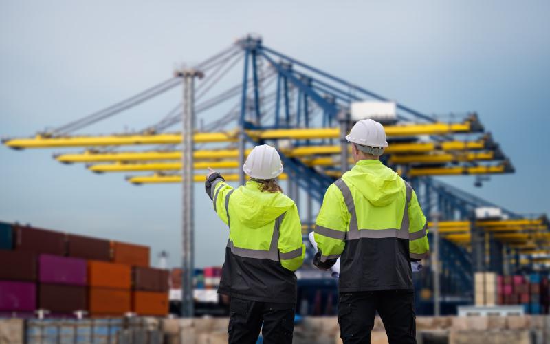 two construction workers looking away toward crane