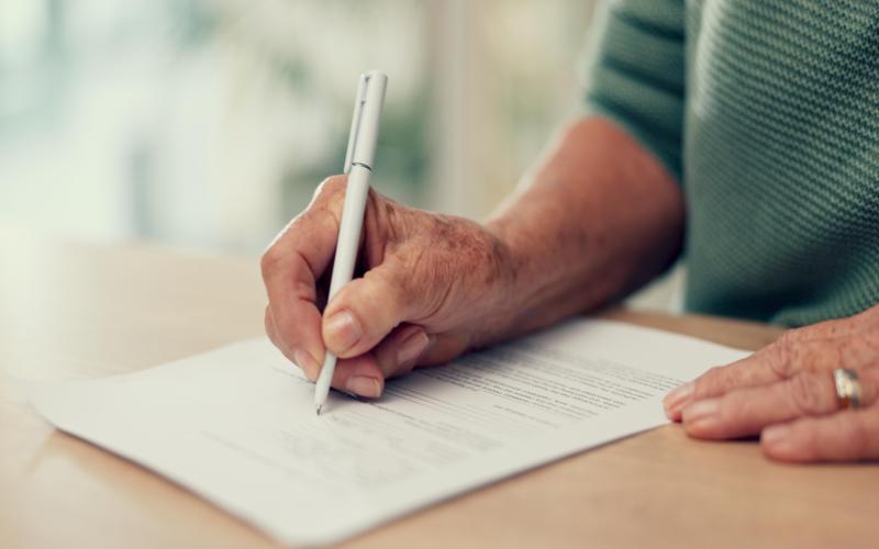 Clos up of person signing a document with their right hand