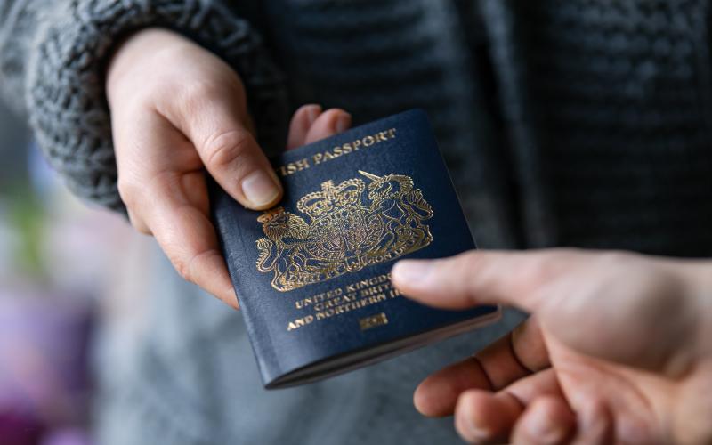 close up of two people exchanging a navy British passport